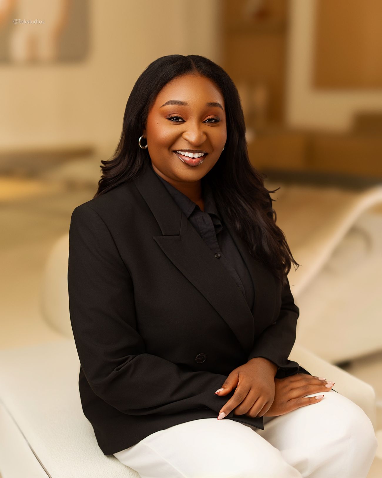 Portrait of Toju Temile smiling, seated in a black blazer